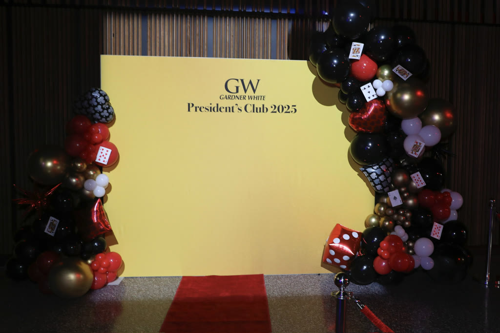Gardner White President's Club casino backdrop with a red carpet and black, red, and gold balloons