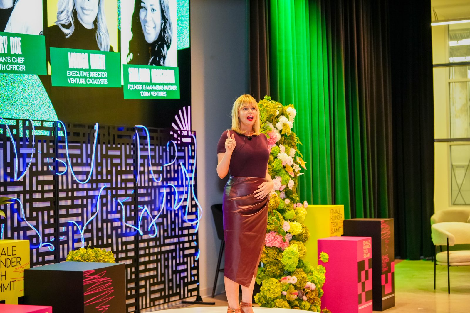 Speaker on stage at the Female Founder Tech Summit with floral column