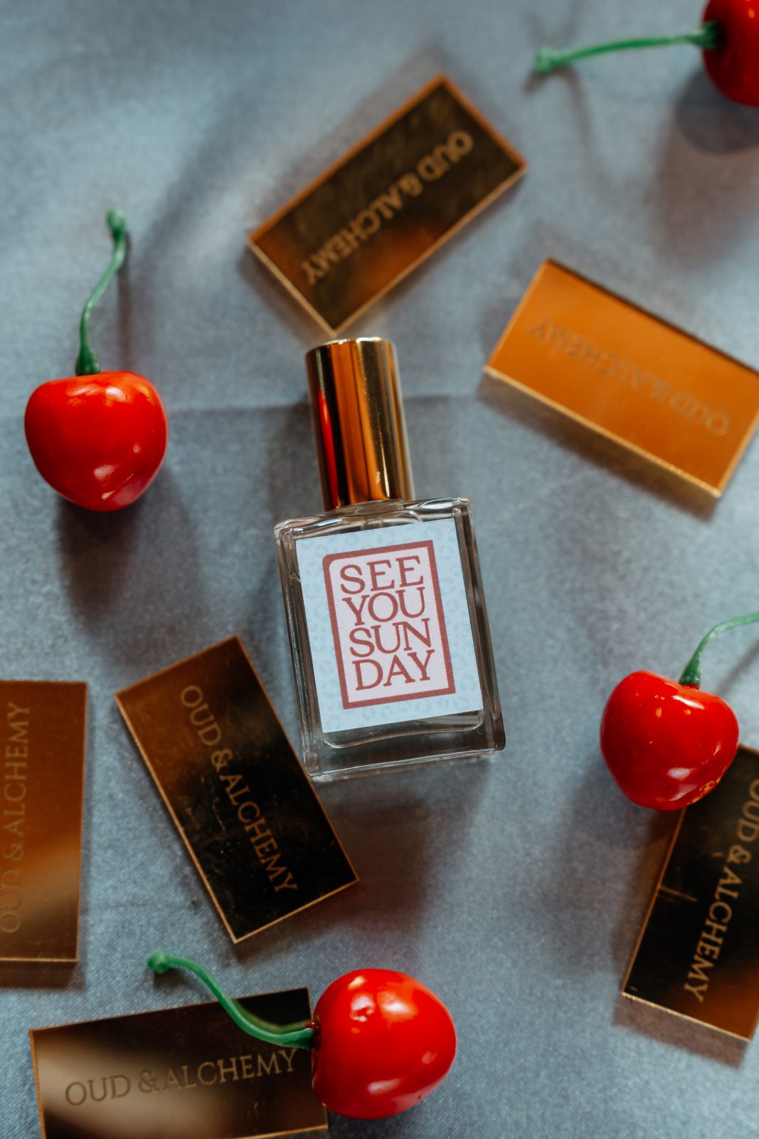 Perfume bottle styled with cherries and gold-foil tags for a fragrance launch