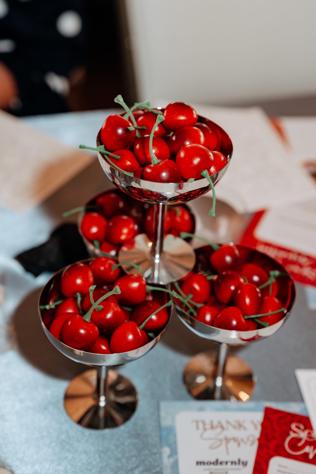 Cherries piled in silver coupe glasses on a tiered display