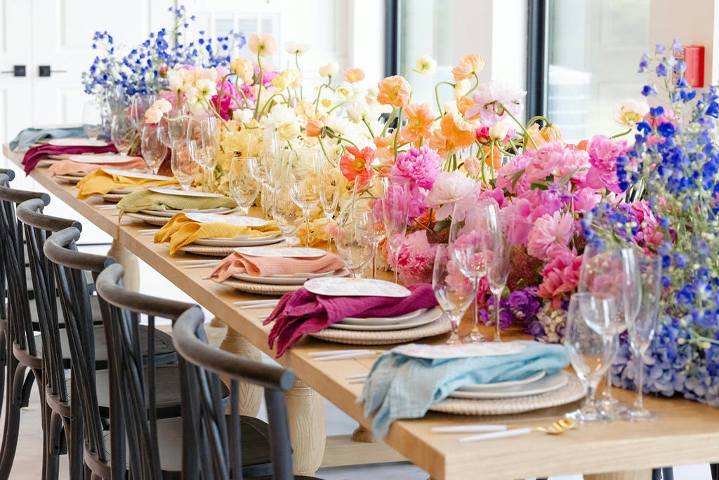 Rainbow ombre floral runner with blue delphinium down a long wooden table