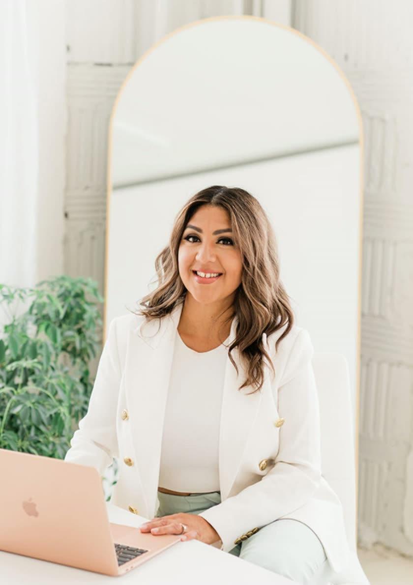 Karla Robles, founder of KRP Events, seated at a desk with a laptop in front of an arched mirror