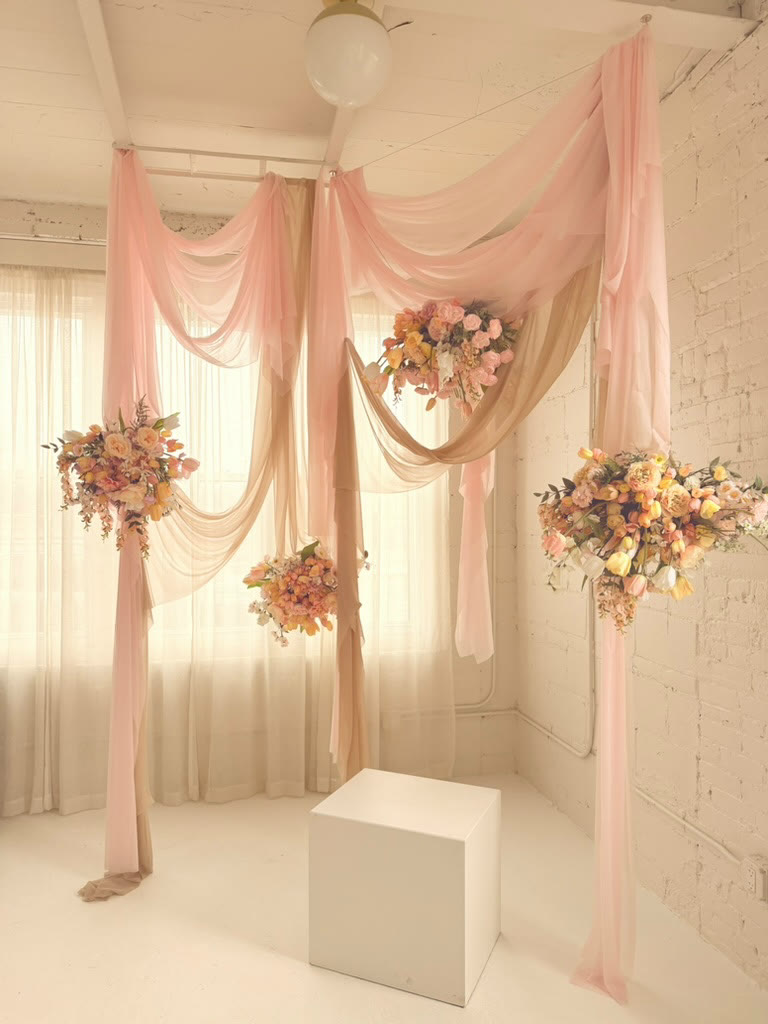 Peach draped ceremony backdrop with three floral clusters