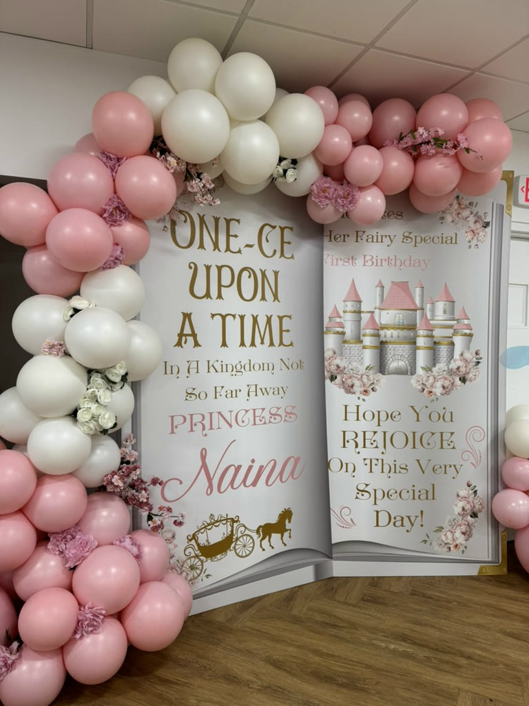 Pink and white balloon arch beside an Once Upon a Time storybook cutout