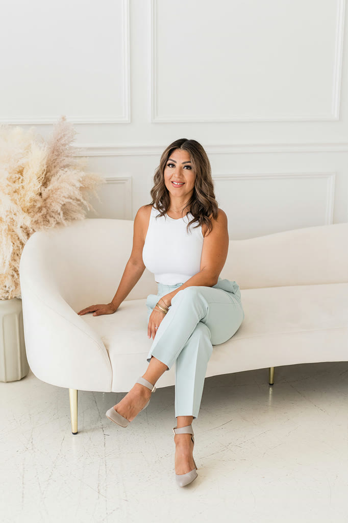 Karla Robles seated on a cream sofa beside pampas grass